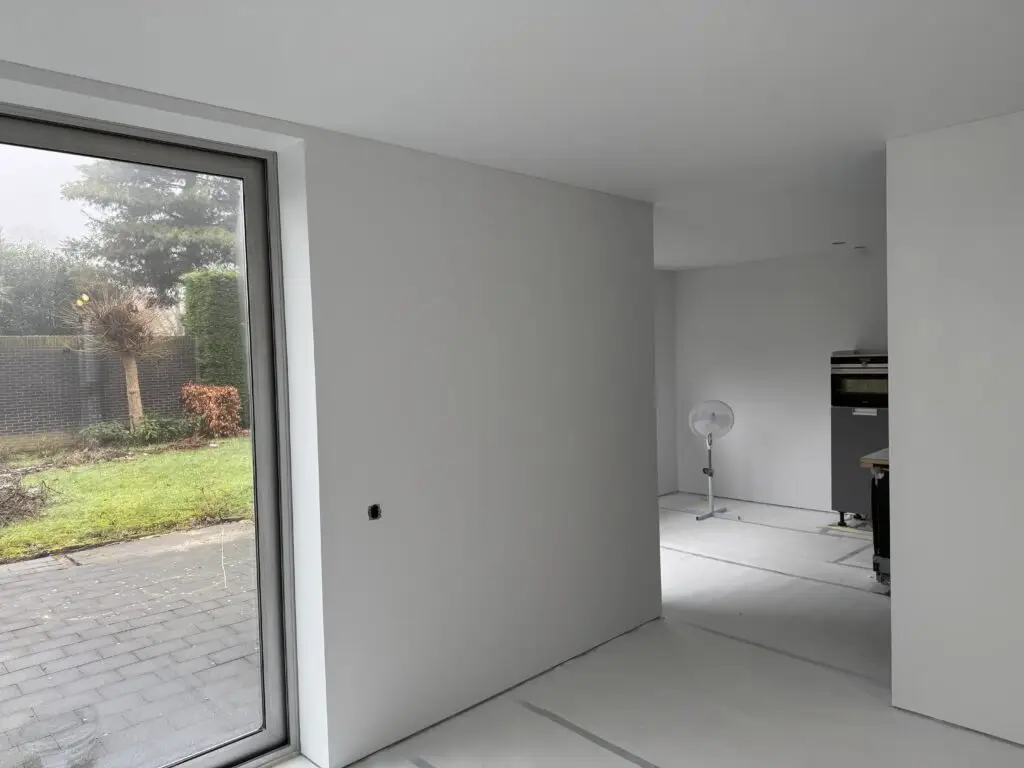 Wit gespoten woonkamer met grote ramen na latex spuiten in Den Bosch